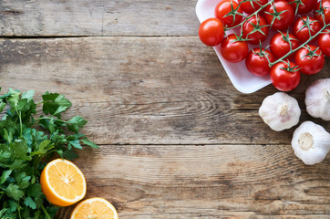 Wall Mural - Ripe cherry tomatoes with fresh herbs, garlic and lemon on wooden background