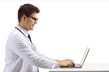 Profile shot of a young male doctor sitting and working on a laptop