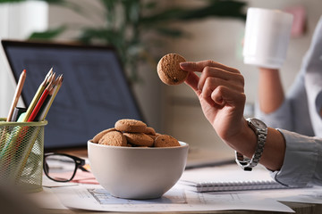 Cloe up of businesswoman eating cookies in the office.