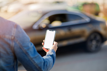 Young business man with phone in car. Man holding smartphone with blank screen .