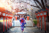 Fototapeta Młodzieżowe - Back view of asia woman with kimono and Japanese umbrella against sakura flower background.