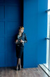 © александр таланцев - a young girl in strict clothes stands near the window and looks out the window