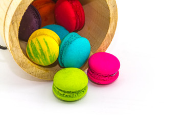 Sweet and colourful french macaroons or macaron stack in bucket wooden isolated on white background.