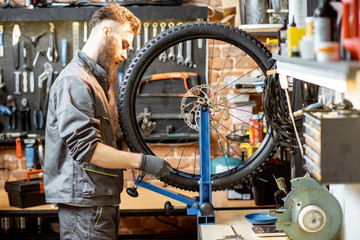 Bicycle service worker aligning wheel with special tool at the workshop of the bicycle shop