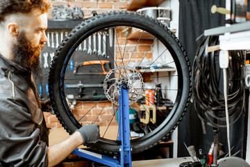 Bicycle service worker aligning wheel with special tool at the workshop of the bicycle shop