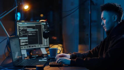 cybercrime, hacking and technology concept - asian male hacker using computer for cyber attack and taking notes in dark room at night