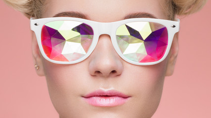 Wall Mural - Portrait of Beautiful young Woman with Colored Glasses. Beauty Fashion. Perfect Make-up. Colorful Decoration. Holographic sunglasses. Coral color