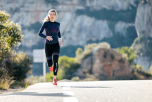 Sporty Young Woman Running On Mountain Road In Beautiful Nature.