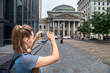 © izikmd - beautiful girl makes a photo against the background of the Bank of Montreal Museum with its dome.