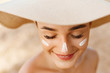 © verona_studio - Woman smile applying sun cream  on face. Skin care. Body Sun protection. Sunscreen. Female in hat smear  moisturizing lotion on skin.Skin Protection and dermatology