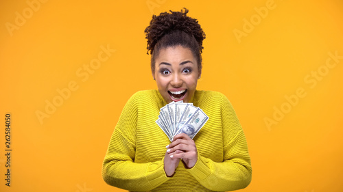 Fotografía Excited Afro-American woman holding bunch of dollars, lottery winner, fortune