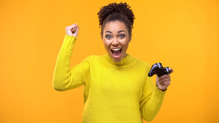 Female teenager showing success gesture enjoying video game, winning round hobby