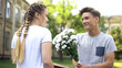© motortion - Teen boy presenting field flowers to teen girl, reading book in city garden