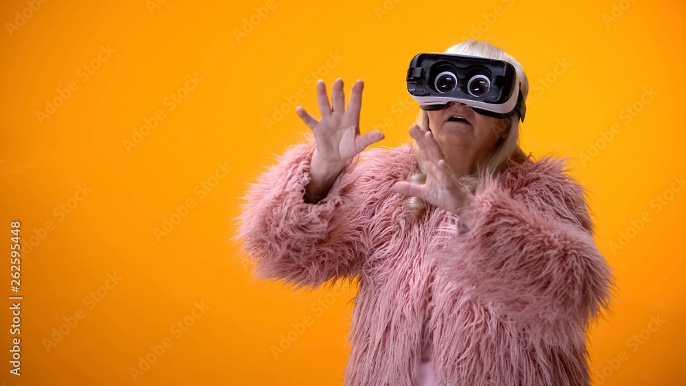 Senior woman in funny coat and VR headset playing video game, hi-end innovations - obrazy, fototapety, plakaty 