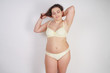 © goldeneden - cute chubby woman in yellow fashion lingerie touching her hair on white background in Studio