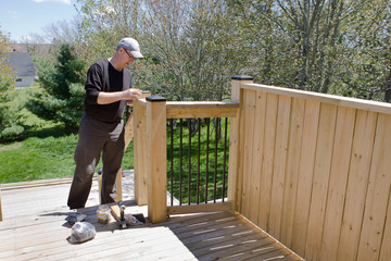  Man works on his deck to put vinyl caps on the top wooden posts