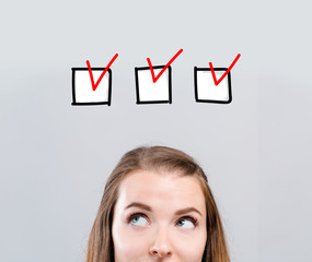 Checklist with young woman looking upwards on a gray background