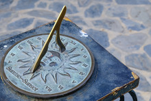 Close-up Of A Brass Sundial Mounted On A Stone Plinth In A Garden, Sundial In The Summer Sun.