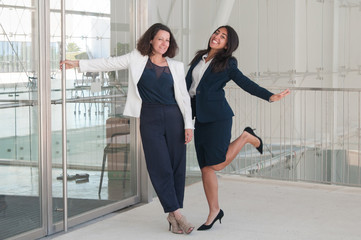 Canvas Print - Two joyful female colleagues standing in office hall