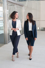 Canvas Print - Two relaxed female colleagues walking in office hall