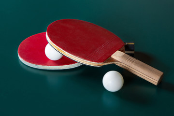 Two ping-pong rackets and a ball on a green table.