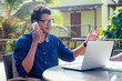 © yurakrasil - man talking on the phone india summer holidays.stylish young indian male freelancer working with laptop freelance surfing online.businessman at remote work on the beach.dream job.online purchase sale