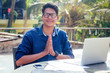 © yurakrasil - handsome and successful indian man in a stylish well-dressed freelancer working with a laptop on the beach.freelance and remote work.businessman student in a summer cafe on the shore of india ocean