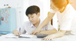 © sirikorn - Asian mother helping her son doing homework on white table.