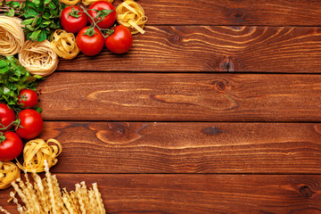 Pasta and ingredients on wooden background with copy space. Top view.