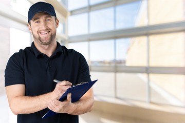 Wall Mural - Delivery man with clipboard on light background