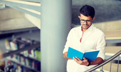 Canvas Print - education, high school, university, learning and people concept - hindu student boy or young man reading book on stairs at library