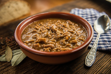 Wall Mural - tripe stew sauce in brown ceramic pot on a wood table 