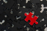 Red jigsaw puzzle piece on black jigsaw puzzle