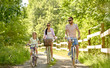 © Syda Productions - family, leisure and people concept - happy mother, father and little daughter riding bicycles in summer park