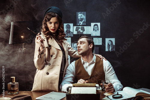 Fotografía Woman with mouthpiece standing near detective in dark office
