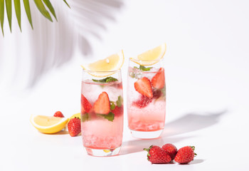 iced strawberry punch cocktail in glass with lemon on white background. summer drink.