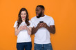 © Yakobchuk Olena - Waist up of interracial couple in white T-shirts holding smartphones in arms
