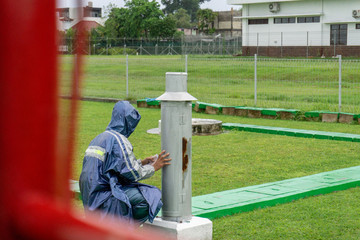 BALI/INDONESIA-DECEMBER 21 2017: A meteorological observer checks the Helman rain meter at meteorology garden to make sure this tool records and works well on rainy day