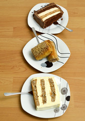 two pieces of a cake and baklava in a three plates on wood background, sweet food concept