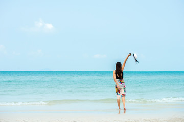 Happy traveller woman in bikini with sun hat enjoys her tropical  vacation on the beach with blue sky  , lifestyle holiday travel  summer concept