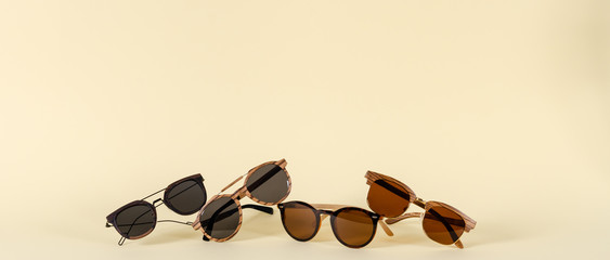 Wooden sunglasses of different design on yellow background. Copy space. Sunglasses sale concept. For banner optic shop