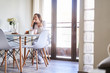 © Fernando Perez/ADDICTIVE STOCK - Attractive young happy woman having breakfast at table near window at home