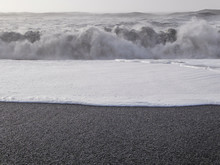 Reynisfjara Is A World-famous Black-sand Beach Found On The South Coast Of Iceland. White Foam Contrasted With Black Sand. Rough Sea Pushes The Foam Far Into The Shore. Dangerous Sea.