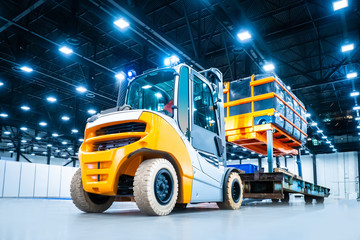 Wall Mural - Diesel loader carries industrial lift with a load. Warehouse loader for transportation of containers. Loading oversized cargo. Transportation of industrial equipment. Special machinery.