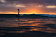 © Olga Sinenko/Stocksy - Silhouette of woman in the ocean surfing wave at sunset. Beautiful clouds. Vivid colors.