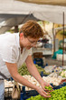 © Saida - Female picking cherry plums at grocery market