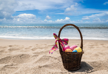 Easter bunny with color eggs on the ocean beach