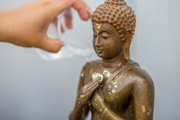 The background of a hand that uses a glass of water, pouring water into the Buddha image, has blurred currents flowing, on the occasion of Songkran Day, New Year and various festivals.