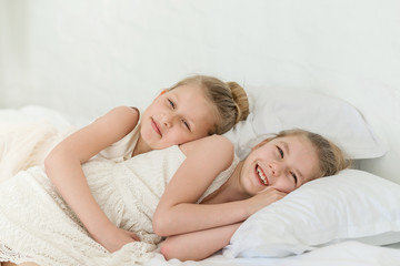 Wall Mural - Two little six years old sisters in the bed lay on the pillows