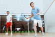 © LIGHTFIELD STUDIOS - Full length view of two sportsmen playing squash with rackets in four-walled court